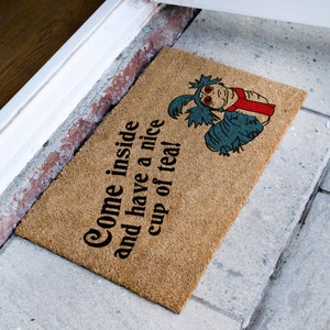 May include: A brown doormat with the text "Come inside and have a nice cup of tea!" and a blue and red cartoon creature.