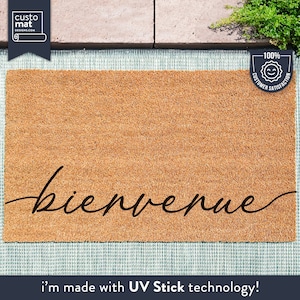 May include: A brown coir doormat with the word "bienvenue" written in black cursive script. The mat is made with UV Stick technology.