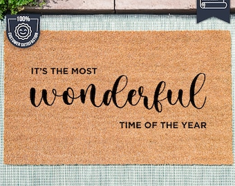 May include: A brown coir doormat with the text "It's the most wonderful time of the year" in black lettering. The mat is made with UV Stick technology.