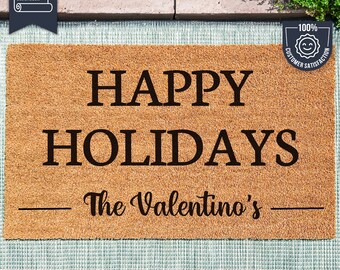May include: A brown coir doormat with the text "HAPPY HOLIDAYS" and "The Valentino's" in black lettering. The mat is made with UV Stick technology.