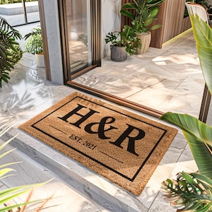May include: A brown coir doormat with black text that reads "H&R EST. 2021". The doormat is on a light gray tiled floor.