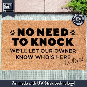 Könnte beinhalten: Eine braune Kokosfaser-Fußmatte mit dem Text "NO NEED TO KNOCK WE'LL LET OUR OWNER KNOW WHO'S HERE - The Dogs" in schwarzer Schrift. Die Fußmatte hat auf jeder Seite des Textes einen Pfotenabdruck.