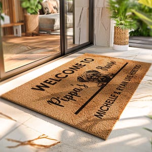 K&ouml;nnte beinhalten: Rechteckige Fu&szlig;matte aus Naturfasern. Der Schriftzug "WELCOME TO Pippa's House" mit einer Mops-Illustration ist zu sehen. Darunter steht "MICHELLE & RYAN LIVE HERE TOO" in schwarzer Schrift.