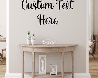 May include: A light wood-toned console table with a half-moon design, featuring a lower shelf and two decorative lanterns. The wall above displays the text "Custom Text Here" in elegant black script. Two white vases and a decorative bowl complete the scene.