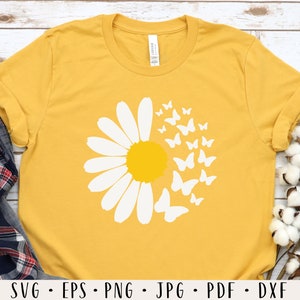 May include: A yellow t-shirt with a white daisy and butterflies design. The daisy has a yellow center and the butterflies are scattered around the daisy.