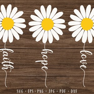 May include: Three white daisy flowers with yellow centers on a brown wood background. The flowers have stems with the words "faith", "hope", and "love" written in white.