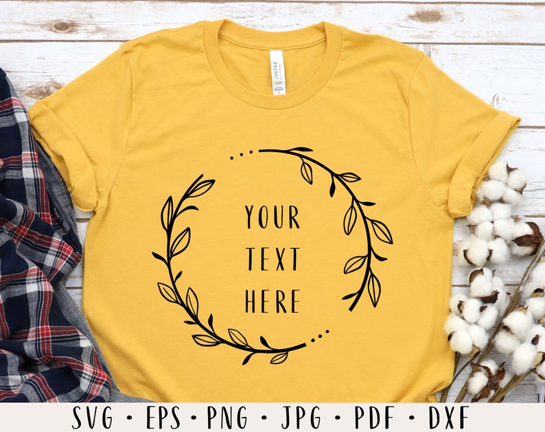 May include: A yellow t-shirt with a black floral wreath design and the text "YOUR TEXT HERE" in the center.