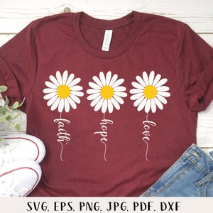 May include: A maroon t-shirt with three white daisies, each with a yellow center. The daisies have stems with the words "faith", "hope", and "love" written underneath them.