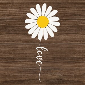 May include: White daisy with a yellow center and the word "love" written in a cursive script below it. The daisy and the word "love" are on a brown wood background.