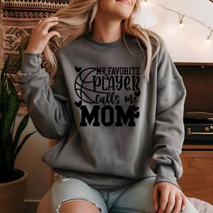 May include: Gray sweatshirt with black text that reads "My favorite player calls me MOM" with a basketball graphic and hearts.