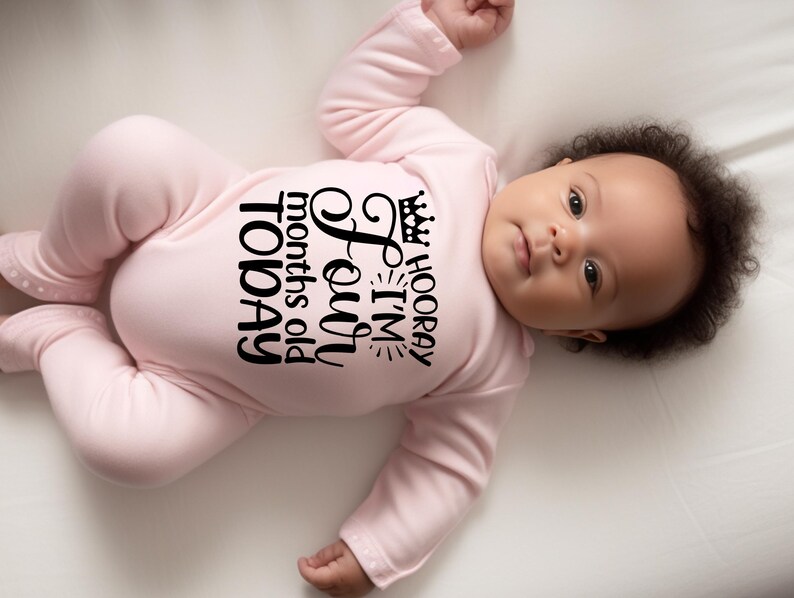 May include: A pink baby onesie with black text that reads 'HOORAY I'M Four months old TODAY' with a crown above the word 'HOORAY'.