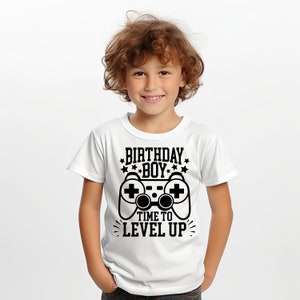 May include: White t-shirt with a black graphic of a video game controller and the text "Birthday Boy" and "Time to Level Up".