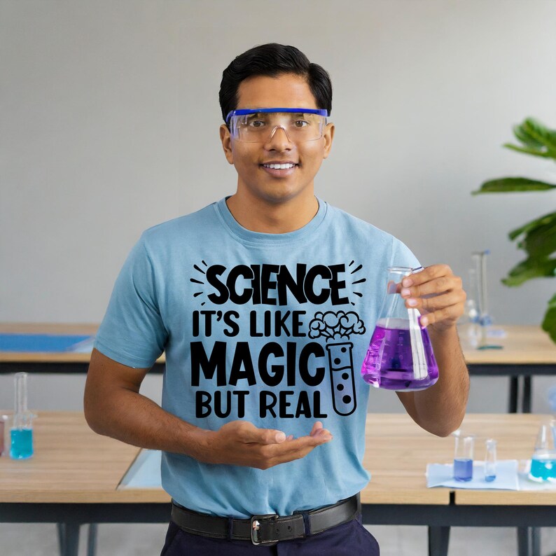 May include: A person wearing a light blue t-shirt with the text "SCIENCE IT'S LIKE MAGIC BUT REAL" and a beaker filled with purple liquid. The person is wearing safety glasses.