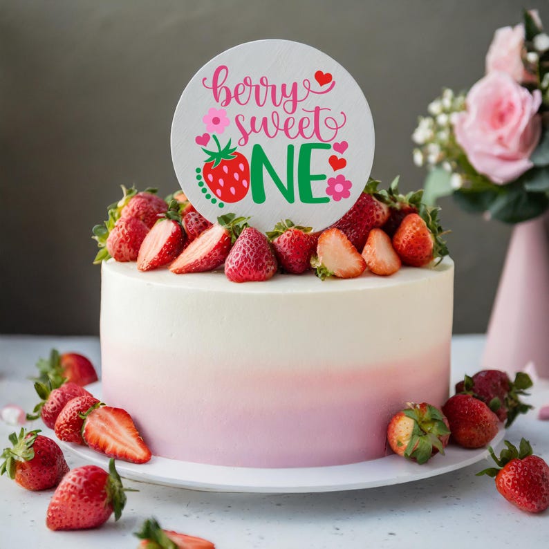 Puede incluir: Un pastel blanco y rosa degradado decorado con fresas frescas y un adorno redondo para pastel que dice "berry sweet one" en letras rosas y verdes con un gr&aacute;fico de fresa.