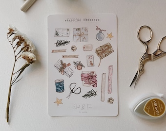 May include: A collection of stationery items for gift wrapping, including a sheet of stickers with illustrations of wrapped presents, a roll of tape, scissors, and a small ink pad. The sticker sheet has the text "Wrapping Presents".