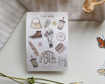 May include: A sheet of stickers with a city walk theme. The stickers feature a baguette, a brown purse, a bouquet of flowers, a donut, a cup of boba tea, a pair of sneakers, a cardigan, a takeout bag, and a paper bag. The stickers are printed on white paper with a light brown background.