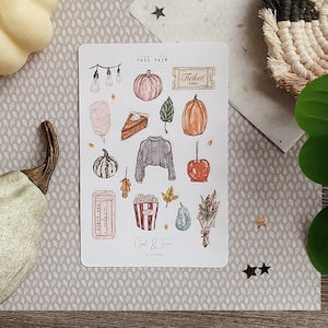 May include: A sheet of stickers with a fall theme. The stickers feature images of pumpkins, leaves, a jumper, a slice of pie, a ticket, popcorn, a candy apple, and more. The text "Fall Fair" is at the top of the sheet.