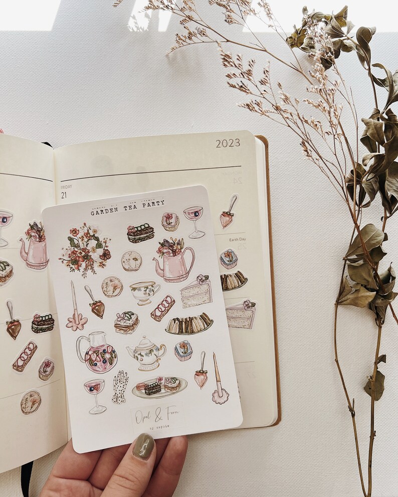 May include: A sheet of stickers featuring watercolor illustrations of tea party elements, including teacups, teapots, cakes, pastries, and flowers. The stickers are labeled "Garden Tea Party" and "Opal & Fern by Sophie".