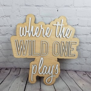 Op de afbeelding: Een houten bord met de tekst "Where the Wild One Plays" in witte letters. Het bord is gemaakt van licht hout en heeft een rustieke uitstraling.