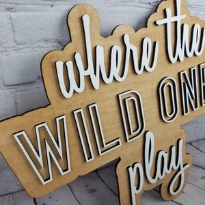 Op de afbeelding: Houten bord met de tekst "Where the Wild Ones Play" in witte letters met zwarte contouren.