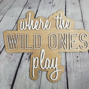 Op de afbeelding: Een houten bord met de tekst "Where the Wild Ones Play" in witte letters. Het bord is gemaakt van lichtbruin hout en heeft een rustieke uitstraling.