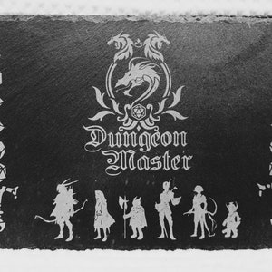 May include: Black and white image of a slate coaster with a dragon and the words "Dungeon Master" engraved on it. There are also images of dice and characters from a role-playing game.