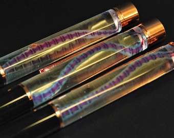 May include: Three clear pens with black barrels and gold accents. Each pen contains a purple and blue iridescent object inside.