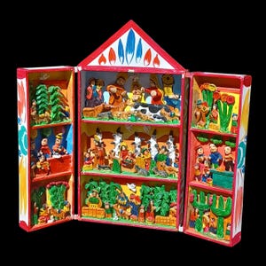 May include: A colorful, three-door, wooden nativity scene. The red-roofed structure features detailed, carved figures and scenes depicting the Nativity story. The doors are decorated with painted patterns and additional carved elements.