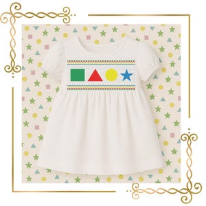 May include: A white short-sleeved dress featuring a smocked chest panel with embroidered colorful shapes including a green square, a red triangle, a yellow circle, and a blue star, bordered by decorative stitching in blue, yellow, and green.
