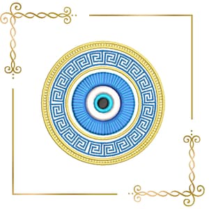 May include: A circular embroidery design featuring a central black pupil surrounded by white, light blue, and dark blue rings. The outer border is a gold Greek key pattern. The design is framed by gold decorative corner flourishes.