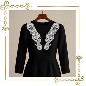 Può includere: Un abito nero a maniche lunghe con scollo rotondo e due applicazioni in pizzo bianco simmetriche sul petto. Il design del pizzo presenta intricati motivi floreali e paisley che si estendono dalle spalle fino alla parte centrale del busto.