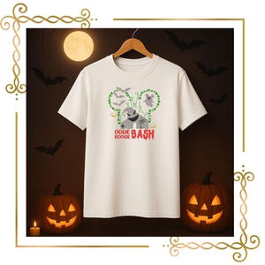 Puede incluir: Una camiseta blanca de manga corta con un gráfico de una silueta de castillo formada por enredaderas verdes, un fantasma, murciélagos y un personaje con cara cosida. El texto OOGIE BOOGIE BASH está impreso en rojo y negro bajo el diseño.