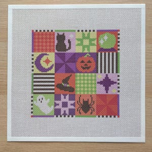 May include: A square needlepoint canvas featuring a grid of sixteen colorful squares with Halloween-themed icons including a black cat, a pumpkin, a ghost, a spider, a witch hat, a crescent moon, a crystal ball, and geometric patterns.