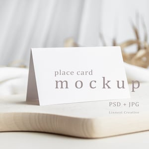 Posizionare il mockup della carta bianca, il mockup della carta bianca vuota, il mockup della cancelleria nuziale, il mockup della carta piegata in stile minimale, la carta del posto tendato sui piatti