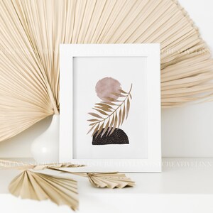 May include: A white framed print with a minimalist abstract design featuring a brown leaf, a pink circle, and a black and white geometric shape.