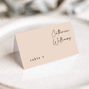 May include: A light pink table card with black text. The text reads "Catherine Williams" and "table 7".
