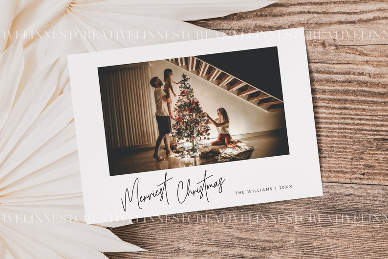 May include: A Christmas card with a photo of a family decorating a Christmas tree. The card reads "Merriest Christmas" and "The Williams | 20XX".
