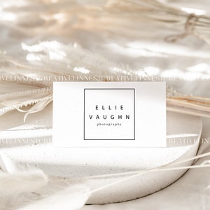 May include: A white business card with black text that reads "Ellie Vaughn Photography" in a square frame.