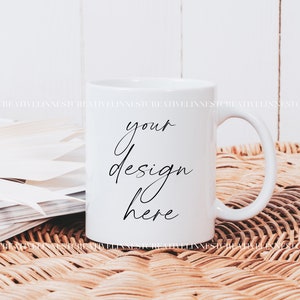 K&ouml;nnte beinhalten: Wei&szlig;e Keramiktasse mit einer schwarzen Aufschrift "your design here" auf einer geflochtenen Weidenoberfl&auml;che.