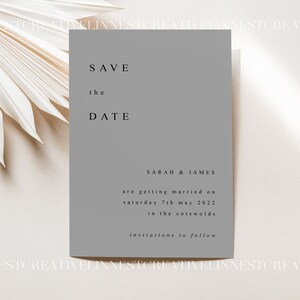 Pu&ograve; includere: Un biglietto di invito grigio con il testo "SAVE the DATE" in caratteri neri. Il biglietto include anche i nomi "SARAH & JAMES" e il testo "are getting married on Saturday 7th May 2022 in the Cotswolds invitations to follow".