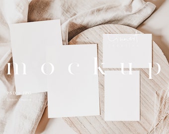 May include: Three blank white cards on a wooden round surface with a beige fabric in the background. The cards are ideal for mockups and branding.