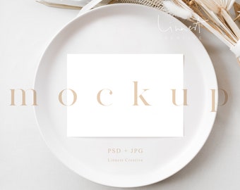 May include: A white card mockup on a white plate with a beige background. The card is blank and has the text "MOCKUP" in beige letters. The text "PSD + JPG" and "Linnest Creative" is also visible in beige letters.