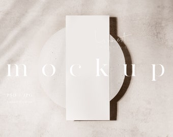 May include: A white card mockup on a round concrete surface with a brown background. The word "MOCKUP" is written in white text on the background.