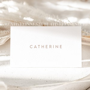 May include: A white business card with the name "Catherine" printed in brown text on a white background.