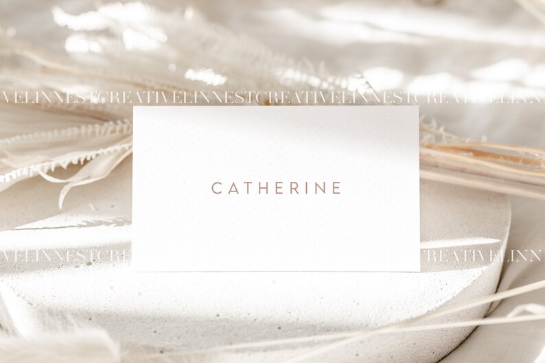 May include: A white business card with the name "Catherine" printed in brown text on a white background.