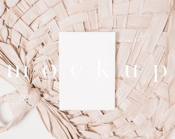 May include: A white card mockup on a woven, light brown, natural material background.
