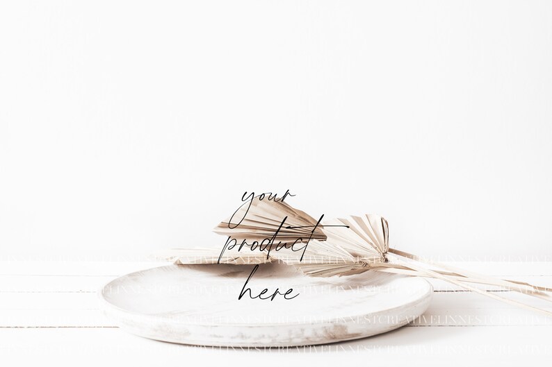 May include: A white ceramic plate with a natural palm leaf arrangement on top. The text "your product here" is written in black cursive on the plate.