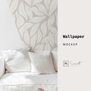 May include: A white couch with two white pillows in front of a wall with a light pink and white leaf pattern wallpaper. The text "Wallpaper Mockup" is on the right side of the image.