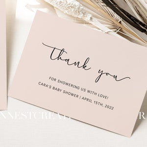 May include: A thank you card with a simple script font that says "Thank you" and the text "For showering us with love! Cara's Baby Shower | April 15th, 2022". The card is a light pink color.