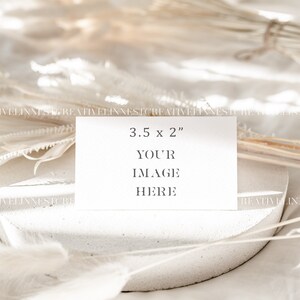 May include: A white card with the text "3.5 x 2" and "YOUR IMAGE HERE" on a white textured surface with white dried flowers.